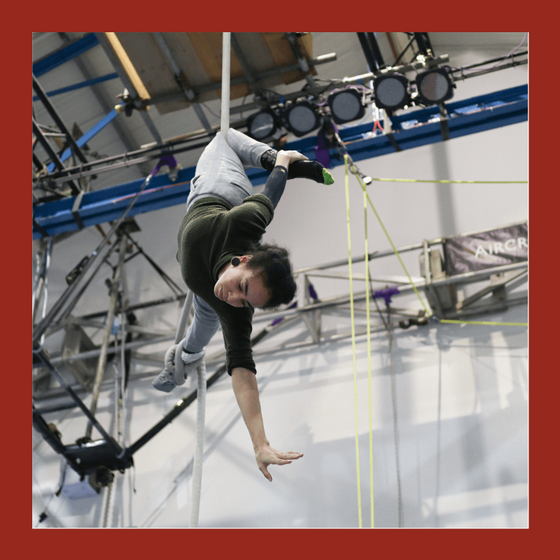aerial rope student holding an upside down position on a white rope