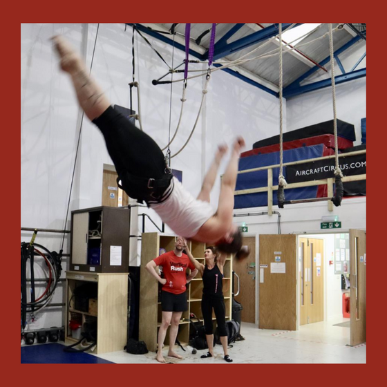 A female student somersaults in a coathanger harness