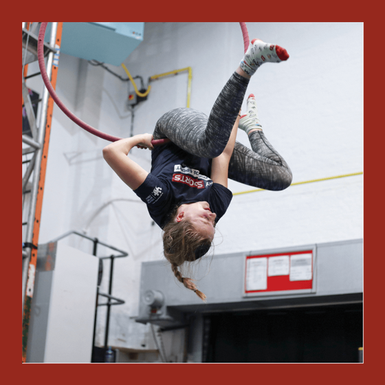 youth student hangs upside down in an aerial hoop
