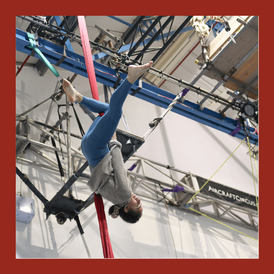 aerial silks student upside down on red silks