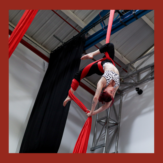 Aerial silks student performs an upside down trick in the silks