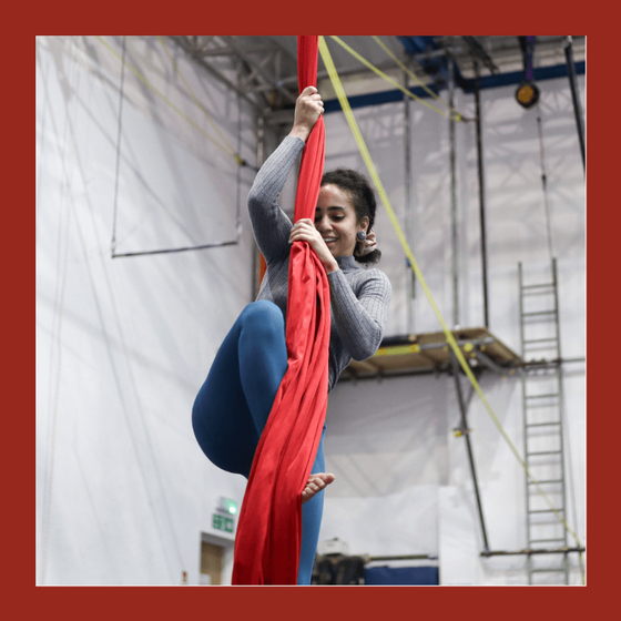 aerial silks student climbs onto red silks