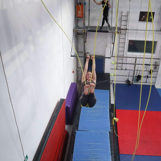 Youth flying trapeze student practices a swing